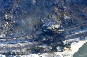 This aerial view of the derailed cars, from a CSX train carrying Bakken crude oil, near Adena Village, W. Va., show limited road access for first responders (near the middle of the frame) and the proximity of the Kanawha River (at the bottom of the frame). Photo information at bottom of post.